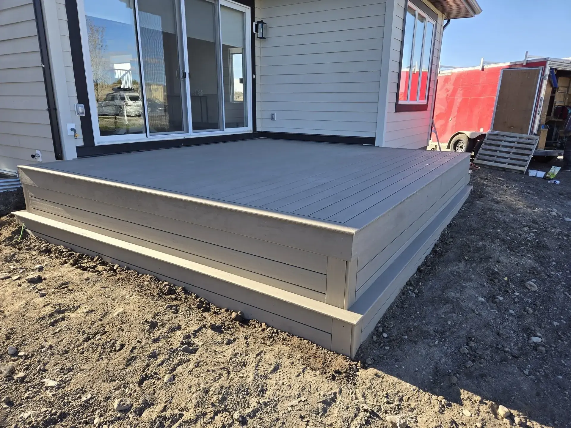 Large backyard composite deck with stairs and railing — Calgary