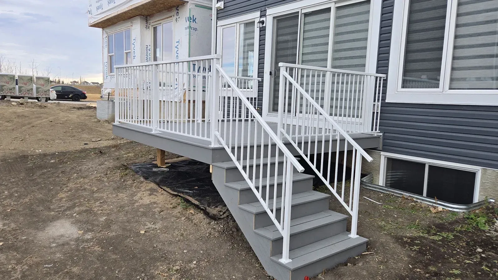 Newly constructed gray wooden deck with white railings and stairs.